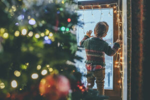 Little boy playing with Christmas lights at home
